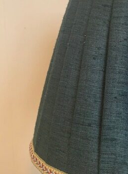 Détail d’un Abat-jour couture à plis plats dans un shantung vert forêt, habillé d’un galon en haut et en bas, réalisé par Sara Marquet