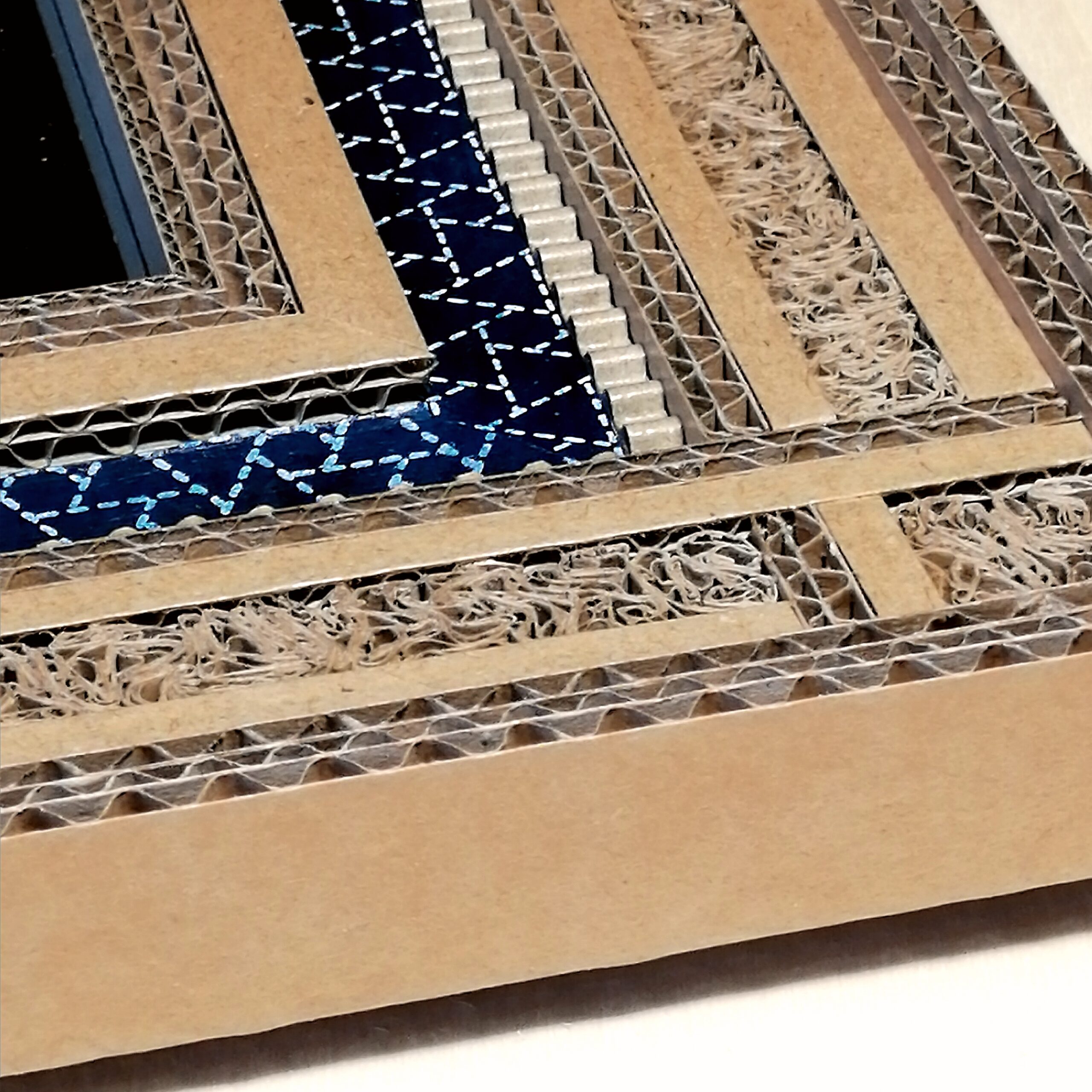 JEMA 2024-autour du carton-détail miroir : détail d'un encadrement de miroir réalisé en dentelle de carton et papier népalais bleu.