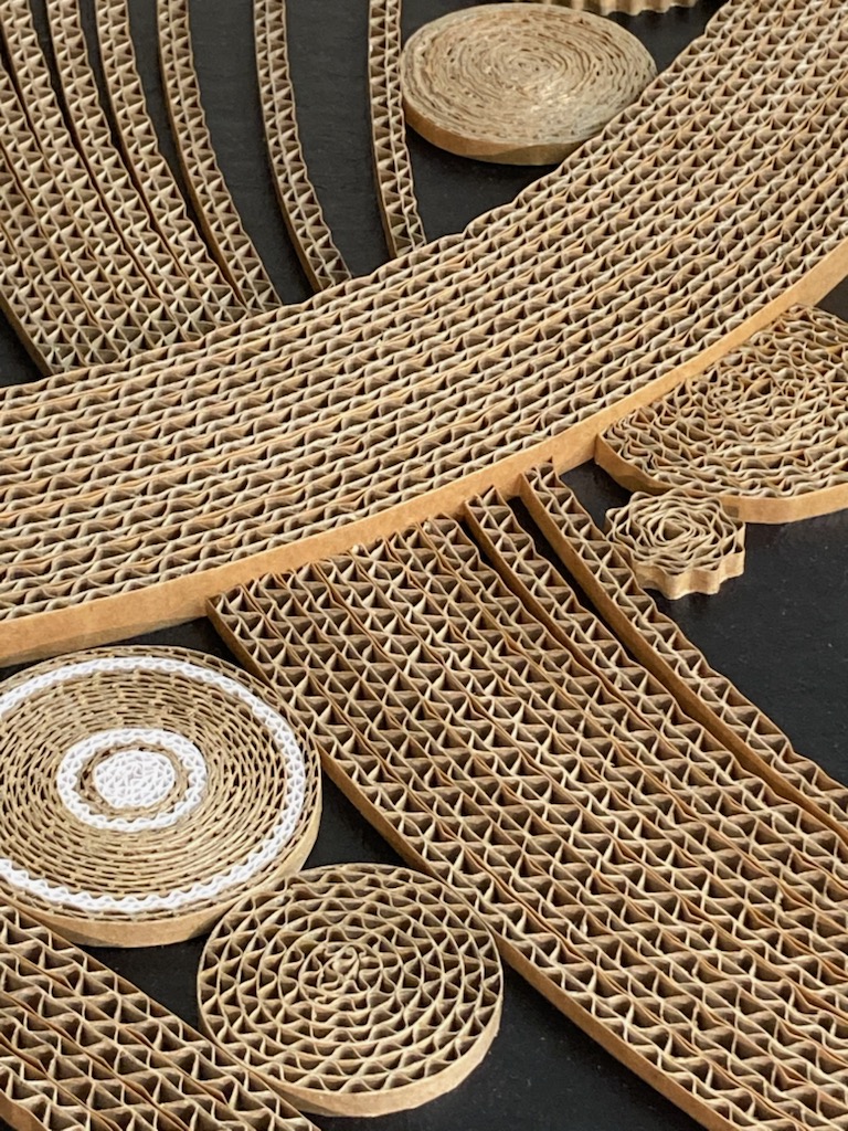 JEMA 2024-autour du carton-détail tableau : Détail d'un tableau abstrait réalisé avec des baguettes de carton courbées ou enroulées sur un fond noir. 