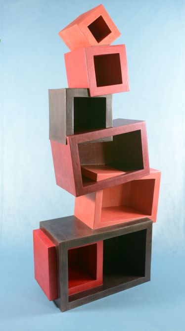 EMA 2024-autour du carton-meuble géométrique : Grand meuble en carton composé de différents cubes et rectangles (tons rouge et brun) empilés les uns sur les autres donnant une impression d'équilibre instable.